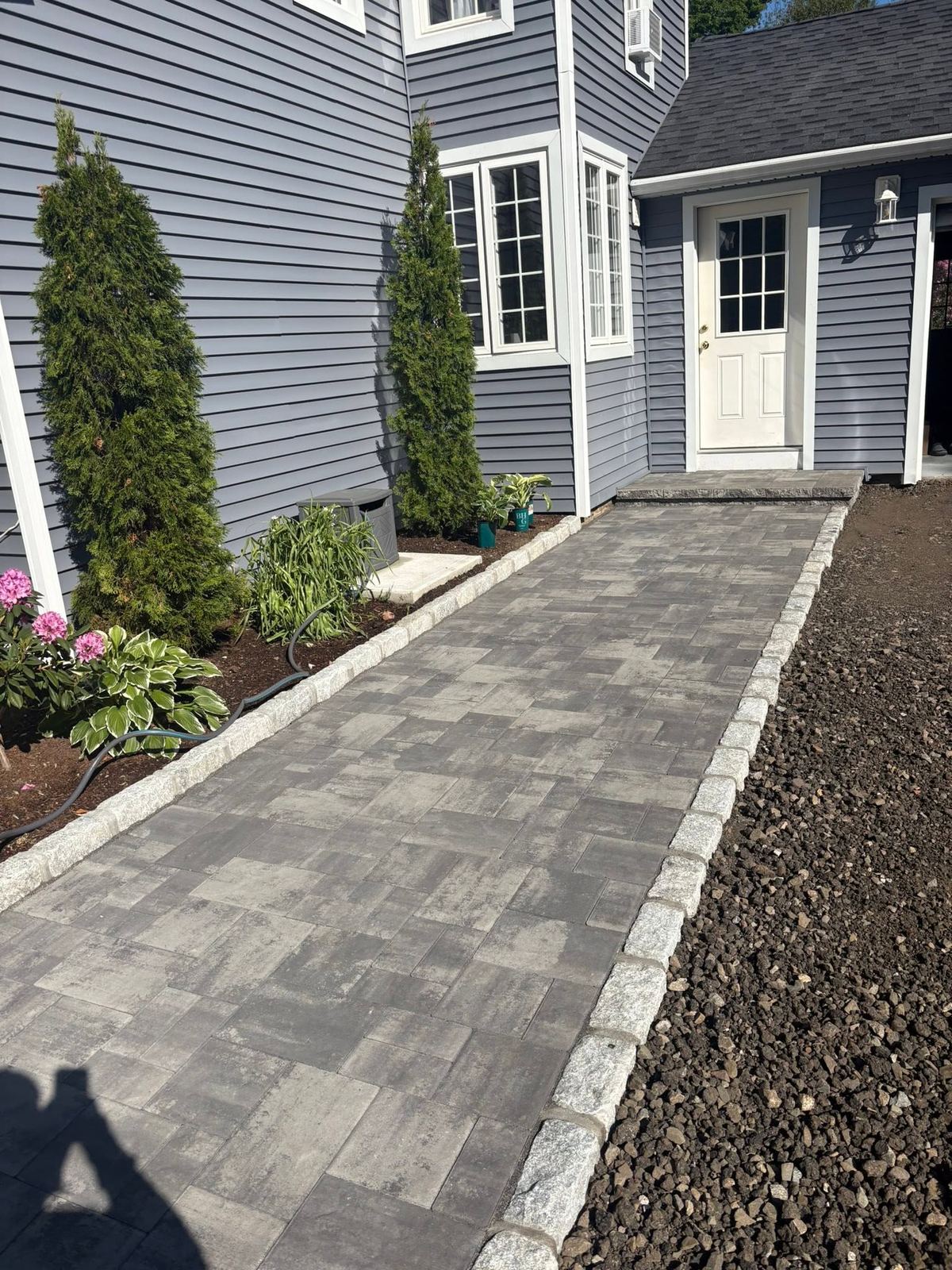 Paver walkway with a granite cobble border leading to a front door